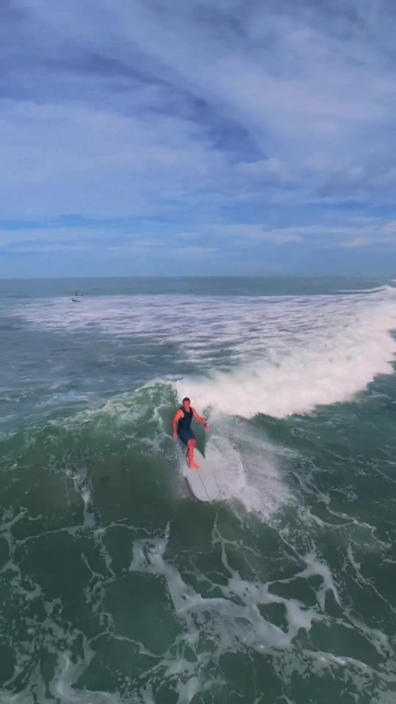 FPV aerial follow tracking a longboarder along a clean wave face at Pipes, Encinitas