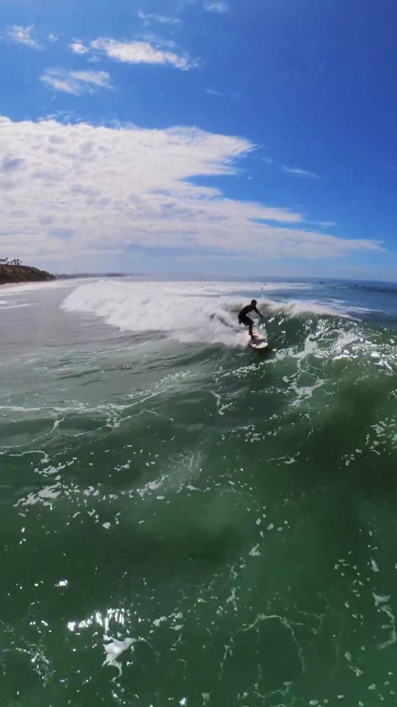 Sustained FPV aerial follow tracking a surfer the full length of a wave at Pipes, Encinitas