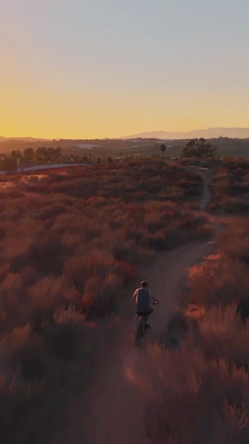 Vertical aerial follow of a mountain biker on singletrack at sunset